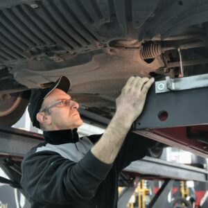Man in Black Jacket Standing Under the Vehicle