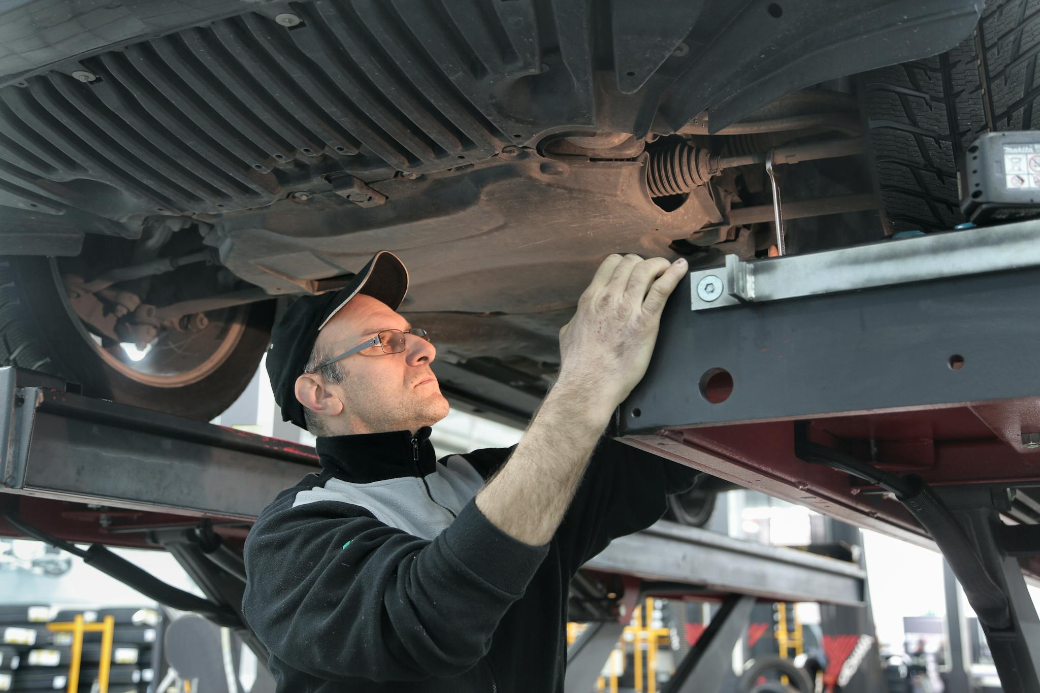Man in Black Jacket Standing Under the Vehicle