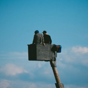 Photo of Two Men on a Crane against Blue Sky
