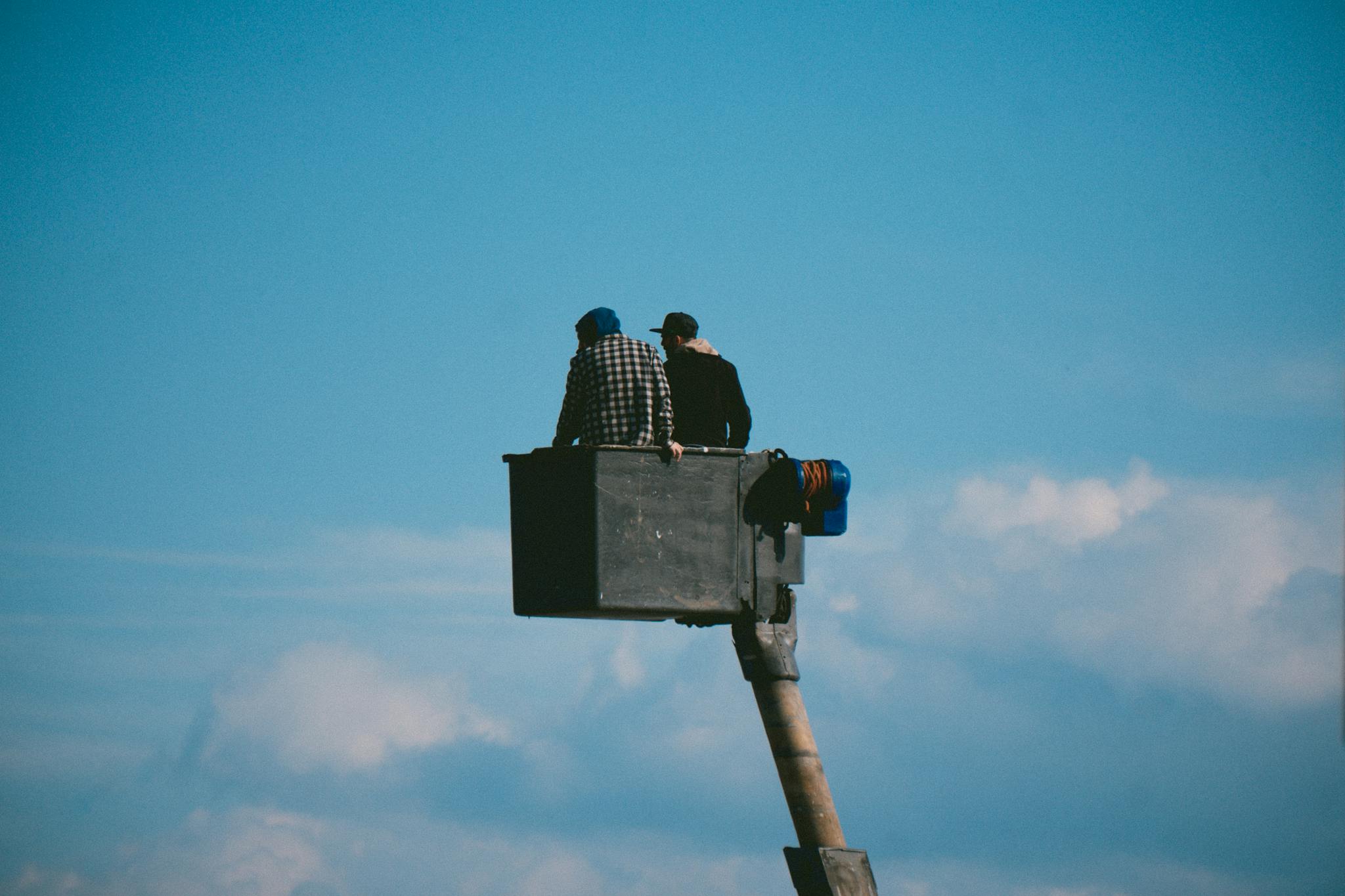 Photo of Two Men on a Crane against Blue Sky